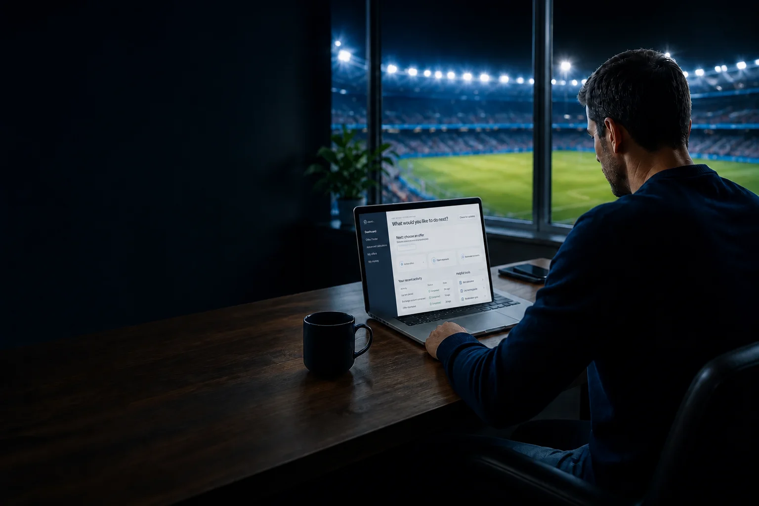 Man seen from behind using a laptop in a stadium hospitality room